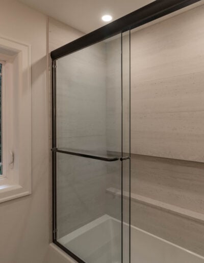 Tub and shower combination with a marble-look tile surround and brushed gold fixtures in a North Bend guest bath