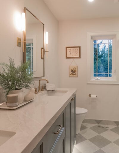 Remodeled guest bathroom in North Bend with a long quartz vanity, sconce lighting and checkerboard tile floor