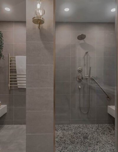 Primary bathroom with a curbless tile shower, built-in bench and heated towel rack