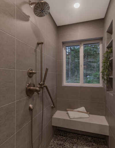Curbless walk-in shower with a pebble tile floor, built-in bench and window