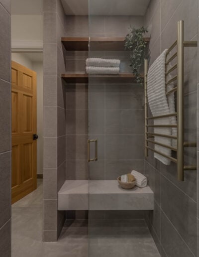 Walk-in shower with floating wood shelf, tile bench and heated towel bar