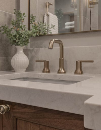 Quartz vanity detail with a brushed gold faucet and undermount sink