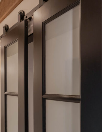 Detail of black steel-framed frosted-glass sliding doors on barn-door track hardware
